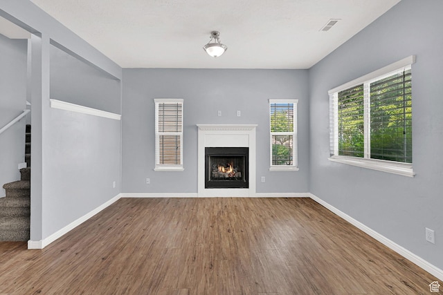 1568 N 565 W Unit 104, Logan, UT 84341 - unfurnished living room featuring stairway, wood finished floors, and a lit fireplace
