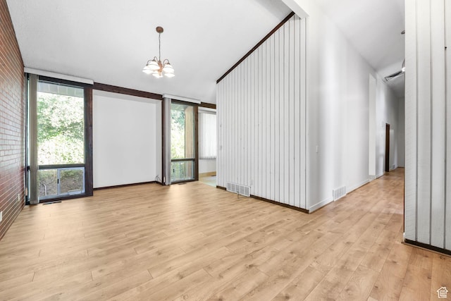 3574 E Kings Cove Way, Cottonwood Heights, UT 84121 - unfurnished room featuring light wood-style floors, a chandelier, brick wall, and a wall mounted AC