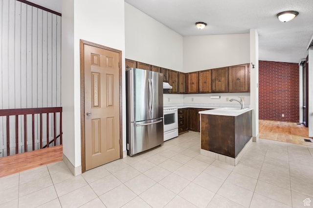 3574 E Kings Cove Way, Cottonwood Heights, UT 84121 - kitchen with freestanding refrigerator, white electric range oven, light countertops, dark brown cabinets, and light tile patterned floors