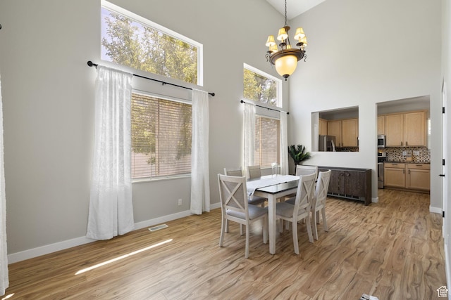 3584 S Autumn Gate Ct, Magna, UT 84044 - dining room with a chandelier, light wood finished floors, a high ceiling, and healthy amount of natural light