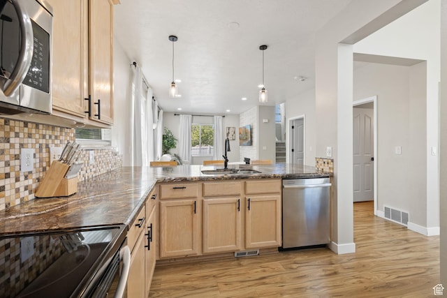 3584 S Autumn Gate Ct, Magna, UT 84044 - kitchen with stainless steel appliances, a peninsula, light brown cabinetry, light wood finished floors, and tasteful backsplash