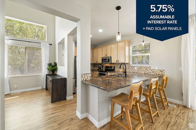 3584 S Autumn Gate Ct, Magna, UT 84044 - kitchen featuring appliances with stainless steel finishes, light brown cabinetry, tasteful backsplash, light wood-type flooring, and a kitchen breakfast bar