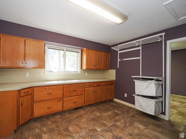 1473 E Millcreek Way, Millcreek, UT 84106 - kitchen with brown cabinetry, light countertops, and stone finish flooring