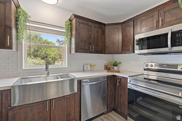 780 N 200 E, Spanish Fork, UT 84660 - kitchen with appliances with stainless steel finishes, dark brown cabinetry, decorative backsplash, light countertops, and light wood-style flooring