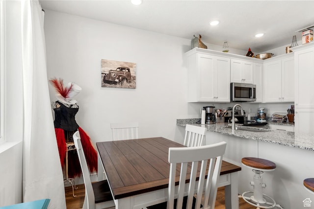 48 E Cedar Ln, Malad City, ID 83252 - kitchen featuring appliances with stainless steel finishes, recessed lighting, light stone countertops, white cabinets, and a breakfast bar