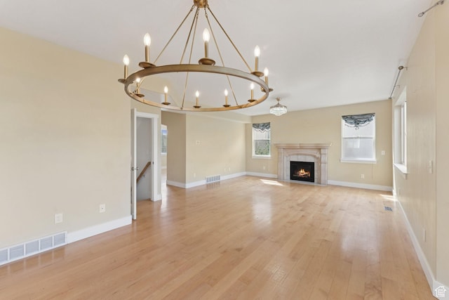 2886 N Desert Forest Ln, Lehi, UT 84043 - unfurnished living room with a chandelier, light wood-style floors, and a tiled fireplace