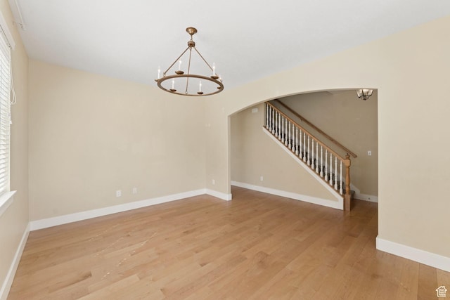 2886 N Desert Forest Ln, Lehi, UT 84043 - unfurnished room featuring a chandelier, arched walkways, light wood-style flooring, and stairs
