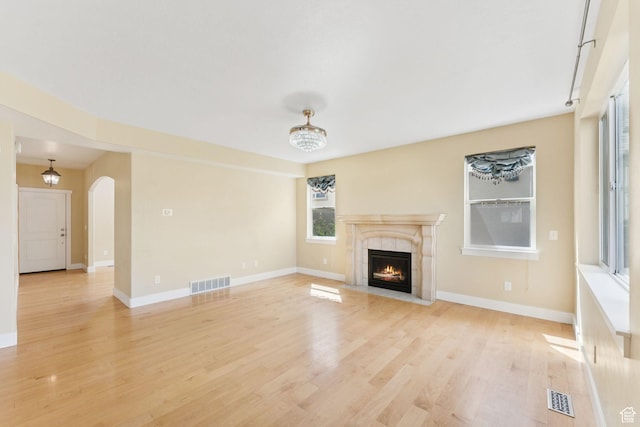 2886 N Desert Forest Ln, Lehi, UT 84043 - unfurnished living room with a tiled fireplace, light wood-type flooring, and arched walkways