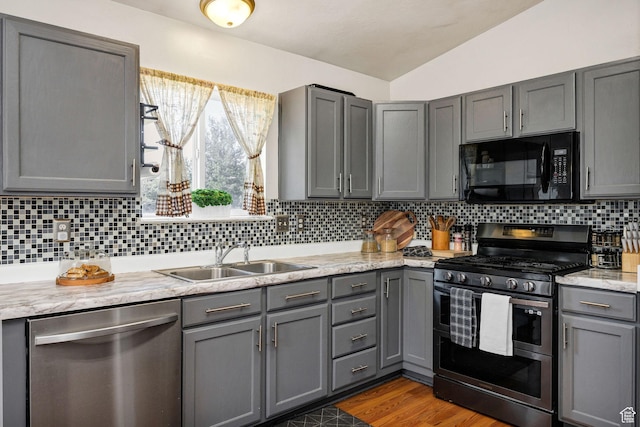 232 Sunstone Cir W, Logan, UT 84321 - kitchen with stainless steel appliances, gray cabinets, lofted ceiling, decorative backsplash, and wood finished floors