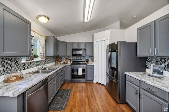 232 Sunstone Cir W, Logan, UT 84321 - kitchen featuring stainless steel appliances, lofted ceiling, gray cabinets, tasteful backsplash, and light wood finished floors