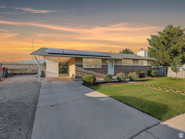 271 S Barratt Cir, American Fork, UT 84003 - view of front of home with driveway, brick siding, a chimney, an attached carport, and roof mounted solar panels