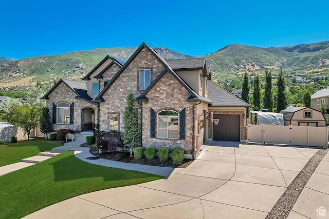 789 Eliza Ct, Farmington, UT 84025 - french country home with concrete driveway, a gate, an attached garage, a mountain view, and stone siding