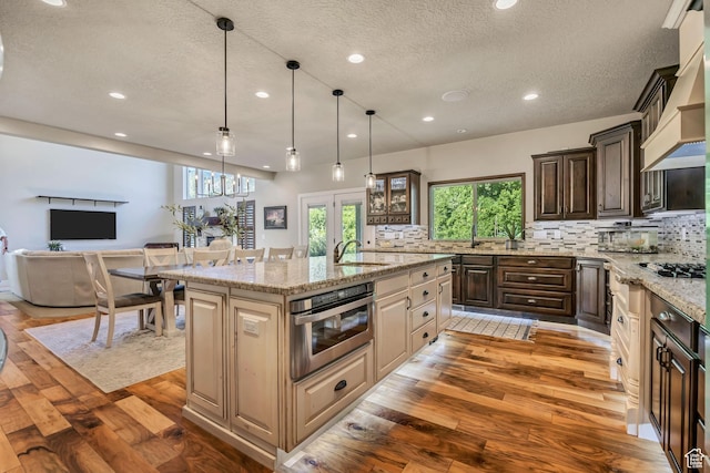 789 Eliza Ct, Farmington, UT 84025 - kitchen featuring light wood finished floors, recessed lighting, a textured ceiling, tasteful backsplash, and a center island with sink