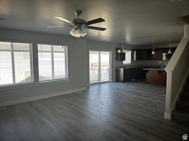 12343 S Varitek Dr, Herriman, UT 84096 - unfurnished living room featuring dark wood-type flooring, a textured ceiling, a chandelier, stairs, and a ceiling fan