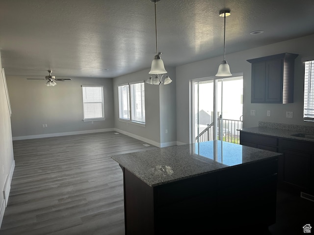 12343 S Varitek Dr, Herriman, UT 84096 - kitchen featuring a textured ceiling, dark wood-style flooring, ceiling fan, a kitchen island, and light stone countertops