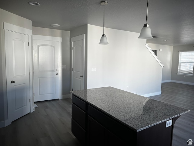 12343 S Varitek Dr, Herriman, UT 84096 - kitchen featuring dark wood-type flooring, a kitchen island, dark stone counters, hanging light fixtures, and a textured ceiling
