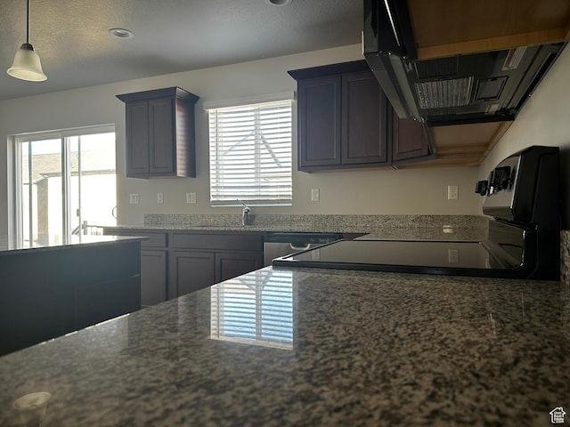12343 S Varitek Dr, Herriman, UT 84096 - kitchen featuring extractor fan, healthy amount of natural light, decorative light fixtures, and dark stone counters