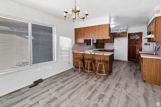 458 E 200 S, Annabella, UT 84711 - kitchen with a peninsula, light wood-style flooring, a chandelier, and brown cabinets