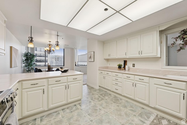 48 W 300 S Unit 1405N, Salt Lake City, UT 84101 - kitchen featuring stainless steel gas stove, a chandelier, light countertops, a peninsula, and white cabinetry