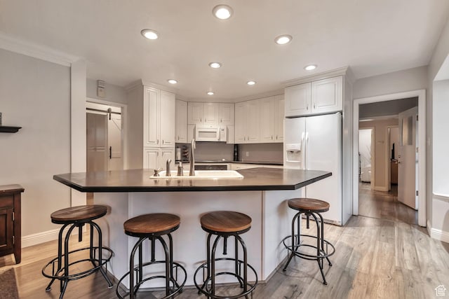 3161 S 8520 W, Magna, UT 84044 - kitchen featuring white appliances, a barn door, white cabinetry, light wood-style flooring, and recessed lighting