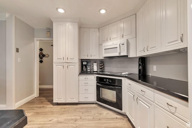 3161 S 8520 W, Magna, UT 84044 - kitchen featuring oven, white microwave, white cabinetry, dark countertops, and light wood-type flooring