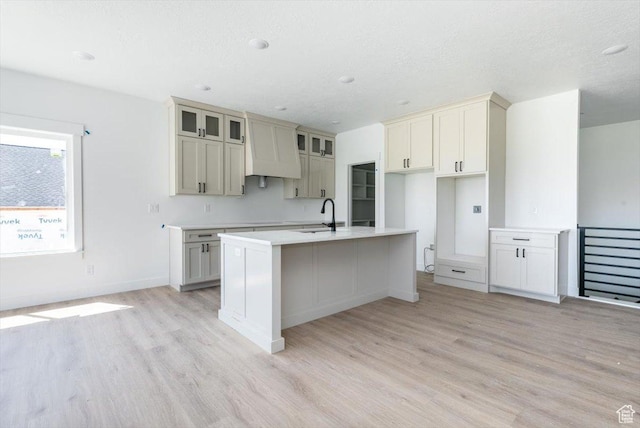 880 E 130 N, Hyde Park, UT 84318 - kitchen featuring light wood finished floors, an island with sink, glass insert cabinets, and light countertops
