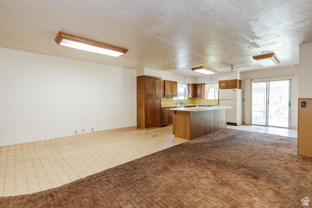 85 E 500 S, Providence, UT 84332 - kitchen with freestanding refrigerator, a kitchen island, brown cabinetry, light countertops, and a textured ceiling