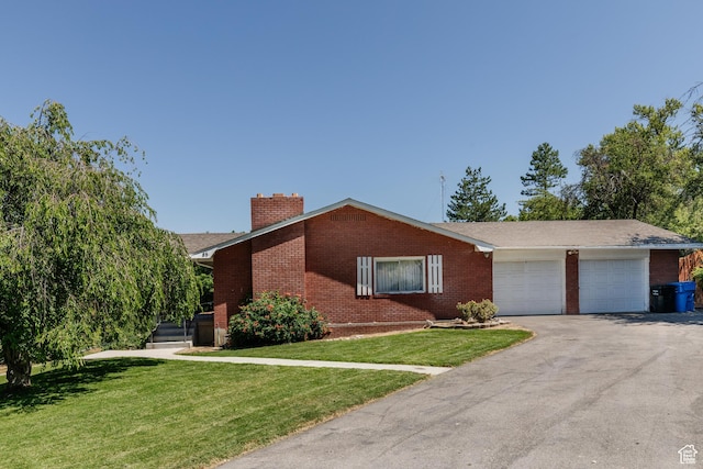 85 E 500 S, Providence, UT 84332 - view of front facade featuring brick siding, a front lawn, a chimney, a garage, and asphalt driveway