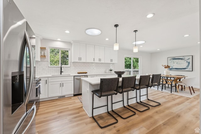 932 W Walden Meadows Dr S, Salt Lake City, UT 84123 - kitchen featuring stainless steel appliances, light countertops, tasteful backsplash, light wood-style floors, and white cabinetry