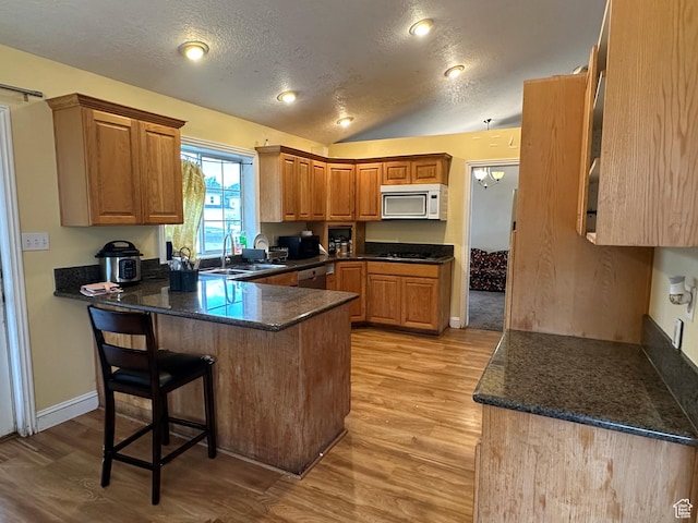 83 E 1820 S, Orem, UT 84058 - kitchen with white microwave, a peninsula, light wood-style flooring, a textured ceiling, and a breakfast bar