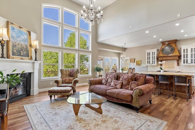 1711 N Compton Rd, Farmington, UT 84025 - living area with a chandelier, wood finished floors, recessed lighting, a high ceiling, and a glass covered fireplace