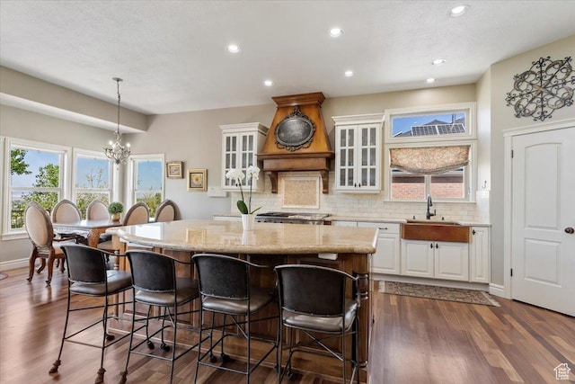 1711 N Compton Rd, Farmington, UT 84025 - kitchen with a kitchen breakfast bar, backsplash, a kitchen island, light stone counters, and white cabinets