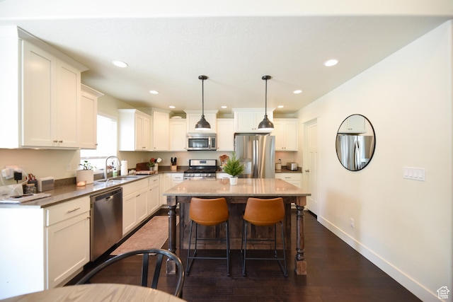 1090 E 770 S, Heber City, UT 84032 - kitchen featuring appliances with stainless steel finishes, a breakfast bar area, dark wood-style flooring, a center island, and white cabinetry