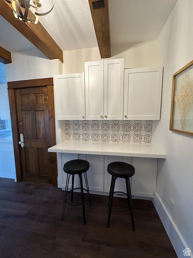 380 N K St, Salt Lake City, UT 84103 - kitchen featuring beamed ceiling, white cabinetry, decorative backsplash, a kitchen breakfast bar, and light countertops