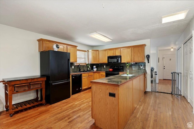2793 S Cyprus Grove Cir W, Magna, UT 84044 - kitchen featuring black appliances, light wood-style flooring, a peninsula, tasteful backsplash, and tile countertops