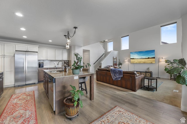 499 N Stone Ridge Dr, Saratoga Springs, UT 84045 - kitchen with appliances with stainless steel finishes, open floor plan, light stone counters, recessed lighting, and a center island with sink