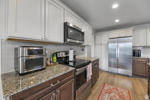 499 N Stone Ridge Dr, Saratoga Springs, UT 84045 - kitchen with stainless steel appliances, tasteful backsplash, white cabinets, light wood finished floors, and light stone countertops