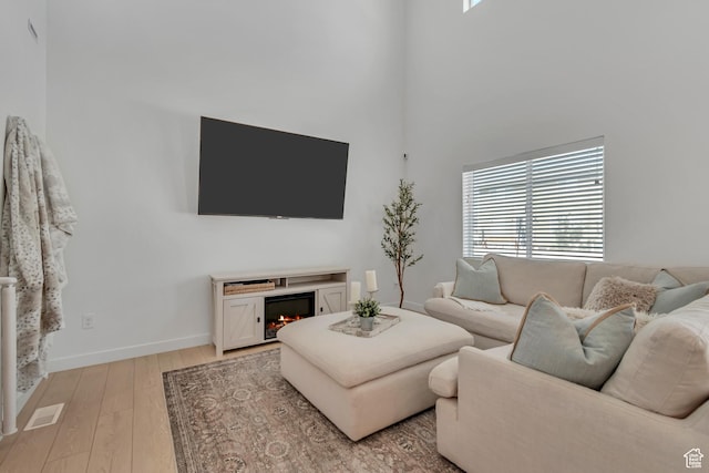 3444 Sparrow Ln W Unit 164, Eagle Mountain, UT 84005 - living area featuring plenty of natural light, a lit fireplace, light wood-type flooring, and a high ceiling
