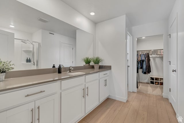 3444 Sparrow Ln W Unit 164, Eagle Mountain, UT 84005 - bathroom with vanity, wood finished floors, a walk in closet, a shower, and recessed lighting