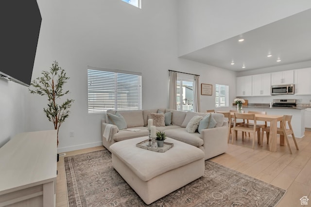 3444 Sparrow Ln W Unit 164, Eagle Mountain, UT 84005 - living room featuring light wood-type flooring, plenty of natural light, a towering ceiling, and recessed lighting