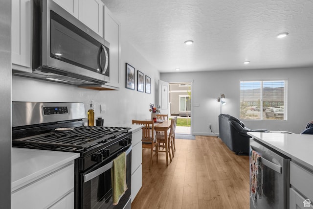943 E Drifter Ln, Saratoga Springs, UT 84045 - kitchen featuring appliances with stainless steel finishes, light countertops, light wood finished floors, white cabinetry, and recessed lighting