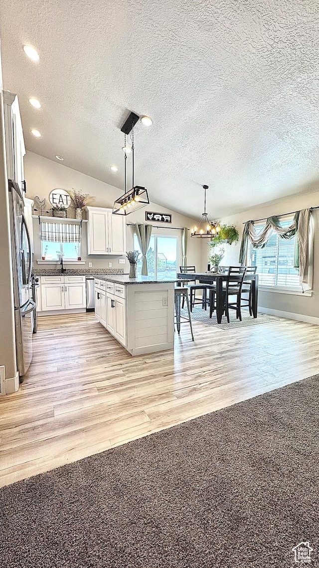 2408 E Maple Dr, Eagle Mountain, UT 84005 - kitchen with appliances with stainless steel finishes, a textured ceiling, white cabinets, light wood-type flooring, and hanging light fixtures