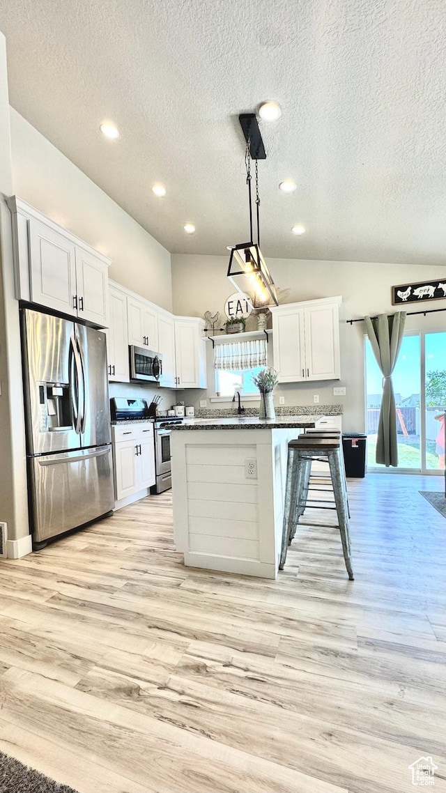 2408 E Maple Dr, Eagle Mountain, UT 84005 - kitchen with stainless steel appliances, dark countertops, a textured ceiling, light wood finished floors, and white cabinetry