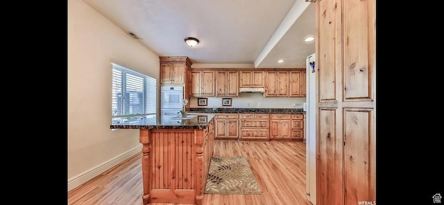2244 S Hunter Dr, Saratoga Springs, UT 84045 - kitchen with under cabinet range hood, light wood-type flooring, a kitchen breakfast bar, gas stovetop, and recessed lighting