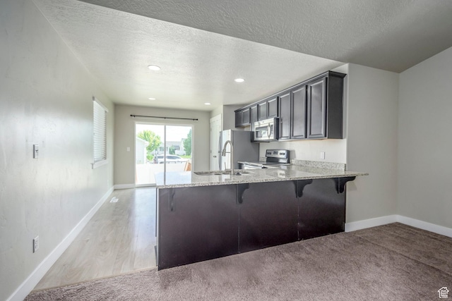 1728 E Shadow Dr, Eagle Mountain, UT 84005 - kitchen with stainless steel appliances, a breakfast bar, light stone countertops, a peninsula, and a textured ceiling