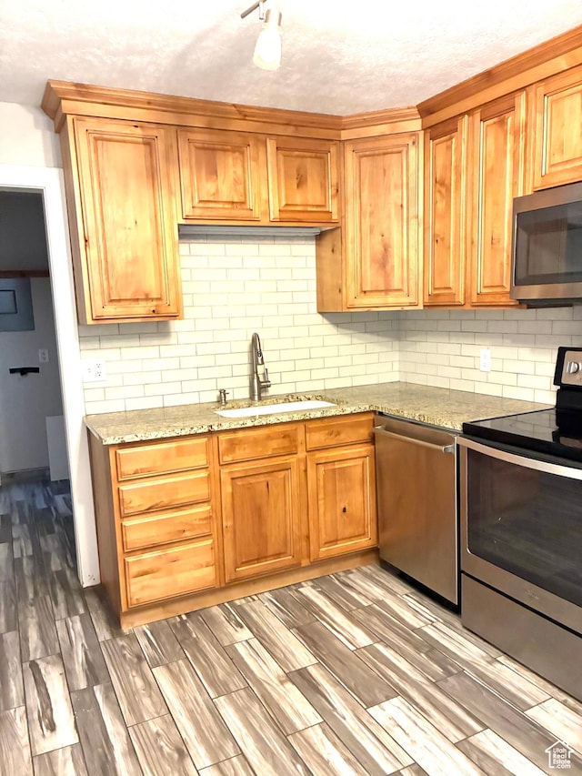 553 Clark St, Woods Cross, UT 84010 - kitchen featuring appliances with stainless steel finishes, decorative backsplash, light wood-style floors, and light stone countertops