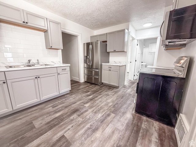 3561 S Grant Ave E, Ogden, UT 84401 - kitchen with appliances with stainless steel finishes, gray cabinets, dark wood-style floors, light countertops, and decorative backsplash