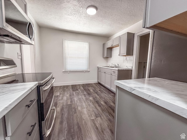 3561 S Grant Ave E, Ogden, UT 84401 - kitchen featuring stainless steel appliances, gray cabinets, dark wood-type flooring, a textured ceiling, and backsplash