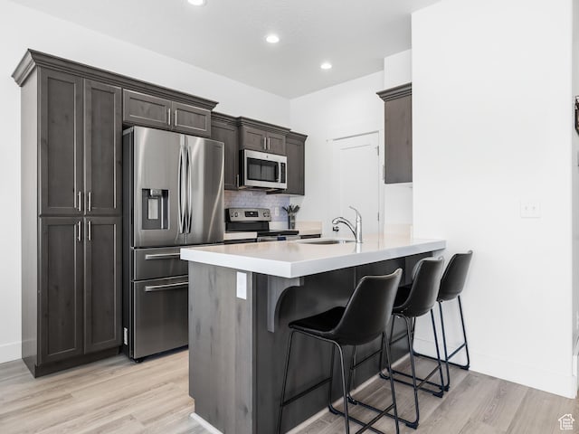 5084 E Lakefield Dr E, Eagle Mountain, UT 84005 - kitchen with appliances with stainless steel finishes, light wood-style flooring, a kitchen bar, a peninsula, and light countertops