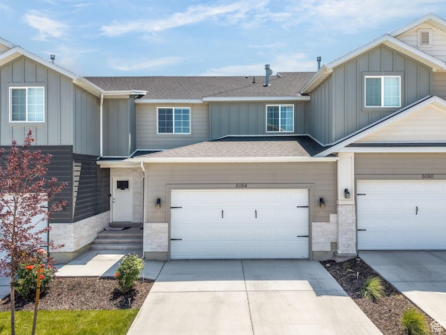 5084 E Lakefield Dr E, Eagle Mountain, UT 84005 - view of front of house with board and batten siding, driveway, a shingled roof, a garage, and stone siding